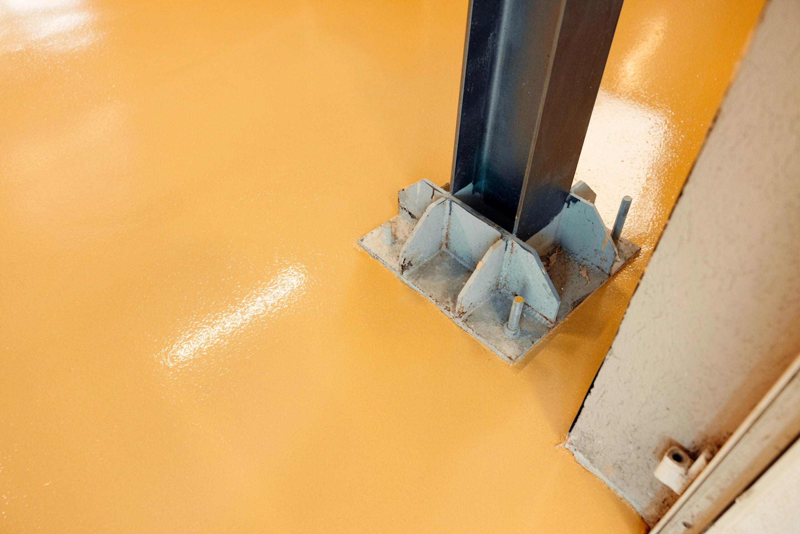 Steel structure standing on shiny orange epoxy resin floor in an industrial building