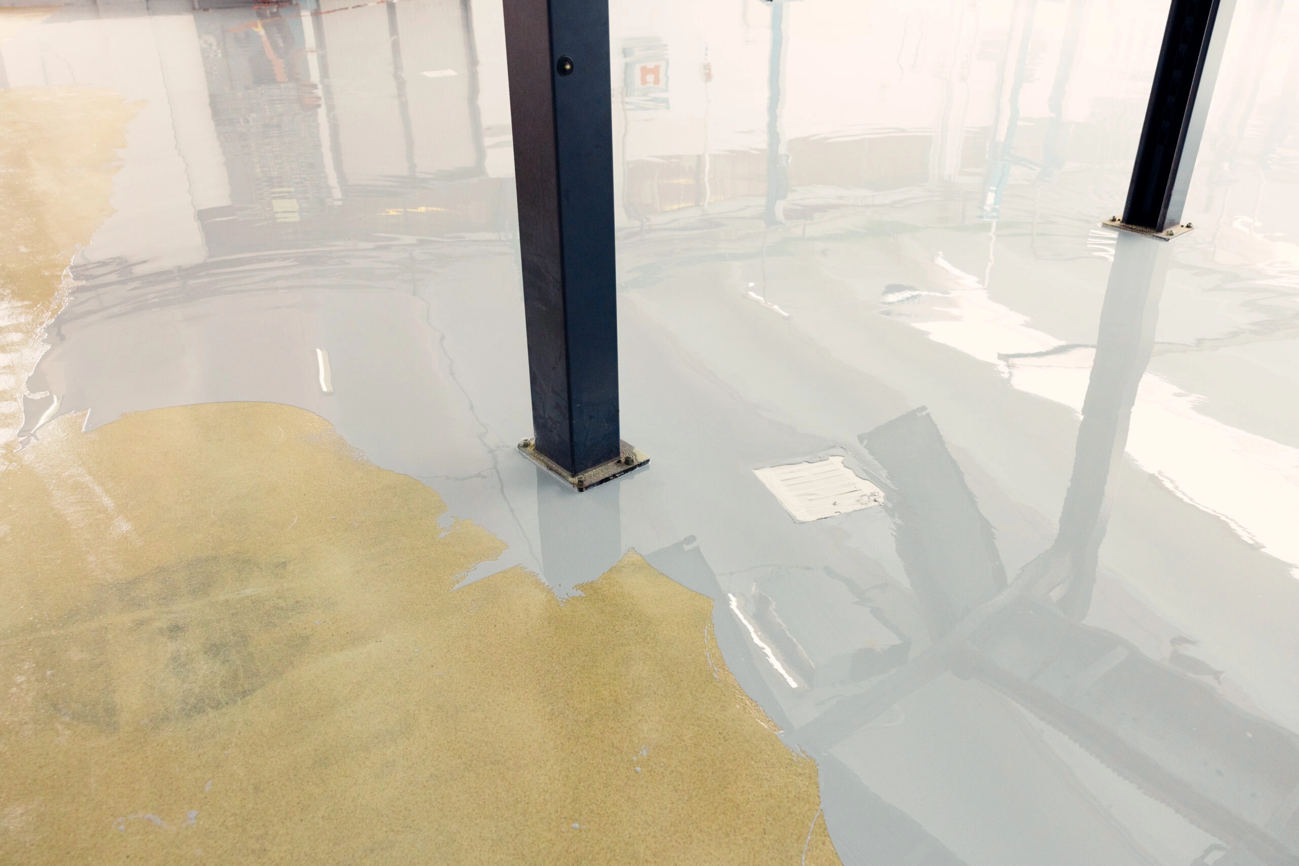 Worker applying epoxy resin to the floor of an industrial facility, creating a smooth and durable surface